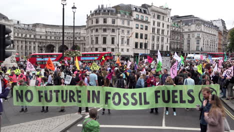 Extinction-Rebellion-climate-change-protestors-hold-a-green-banner-that-says,-“No-future-in-fossil-fuels”-as-hundreds-prepare-to-march-with-flags-and-placards-on-the-first-day-of-protests