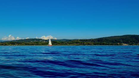 Low-angle-pov-of-small-boat-sailing-in-calm-open-lake-waters-of-Maggiore-lake-in-Italy