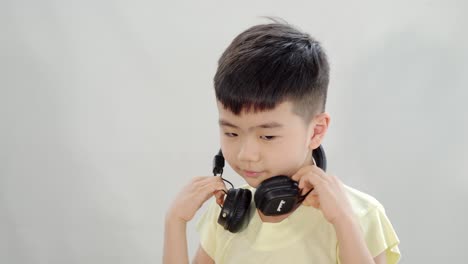 asian-chinese-kid-listening-to-music-with-headphone-and-shake-his-head