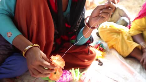 Hands-of-woman-making-traditional-Indian-necklace-with-fabric-flowers,-Rajasthan