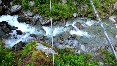 Point-of-view-shot-of-a-men-balancing-on-a-cable-across-a-crystal-clear-river