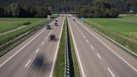 Statischer-Tageszeitraffer-Einer-Schweizer-Autobahn-Inmitten-Grüner-Landwirtschaftsfelder-In-Der-Schweiz