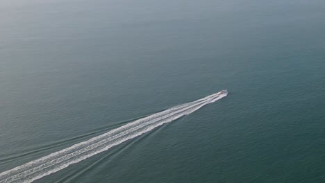 Isolated-speedboat-leaves-white-wake-trail-over-blue-and-calm-sea-water