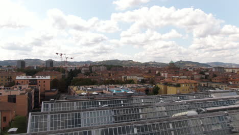 Building-rooftop-greenhouses-with-majestic-view-of-Bologna-city,-aerial-drone-fly-over-view