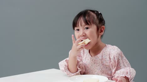 Fröhliches-Asiatisches-Mädchen-Lächelt-Und-Genießt-Es,-Zu-Hause-Knusprigen-Buttertoast-Zu-Essen