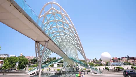 Low-Angle-View-Of-Bridge-Of-Peace-In-Tbilisi-With-Cars-Going-Past
