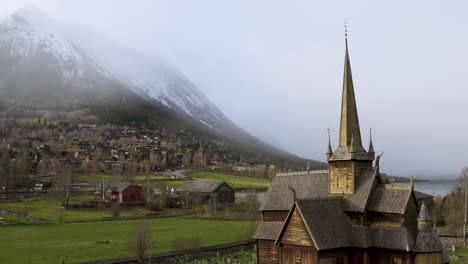 Lom-Iglesia-Medieval-De-Madera-Con-Detalle-De-Techo-Símbolo-Vikingo-Contra-Montañas-De-Nieve-Brumosa-En-Noruega