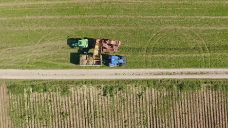 Top-down-shot-at-a-potatoe-collecting-worker-which-is-walking-through-his-green-and-blue-tractors