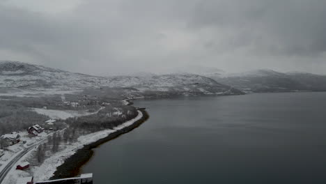 Snowy-Mountain-And-Calm-Waters-Of-Fjord-On-A-Gloomy-Day-During-Winter-In-Northern-Norway