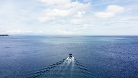 Aerial-drone-flyover-of-dive-motorboat-heading-out-to-beautiful-coral-reef-for-snorkeling-and-diving-in-stunning-secluded-remote-tropical-island-destination