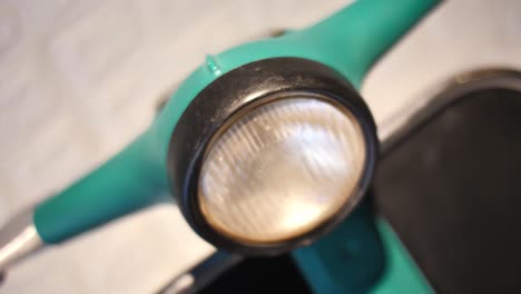 Close-Up-Detail-Of-Vespa-Headlamp-On-Green-Handlebar