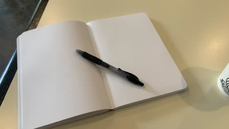 Close-up-shot-of-a-book-with-empty-pages-and-a-pen-resting-on-top