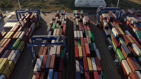 Drone-Flying-Over-Industrial-Port-With-View-Of-Loader-Equipment-And-Stack-Of-Colorful-Shipping-Containers