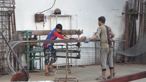 Factory-Worker-Using-Foot-Pedal-To-Action-Spot-Weld-Machine-On-Reinforcement-Wire-In-Karachi,-Pakistan
