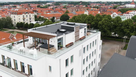 White-Hotel-building-of-Fritiden-in-Ystad-city-with-majestic-rooftop-terrace,-drone-orbit-view