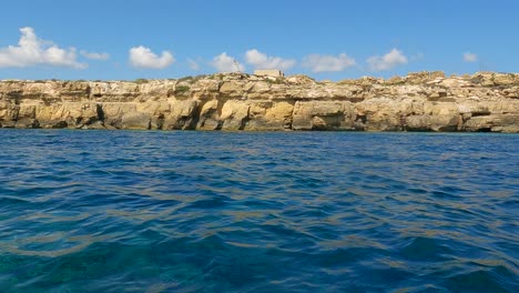Extreme-Low-angle-sea-level-view-from-sailing-boat-of-Favignana-island-coastline-in-Sicily,-Italy