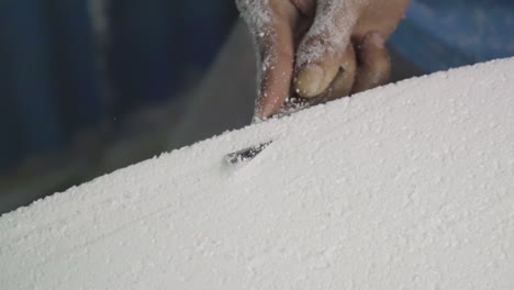 Cutting-through-foam-board-to-build-DIY-surfboard-in-workshop,-close-up-hands