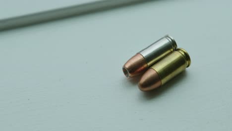 Close-Up-Pan-Right-of-a-Hollow-Point-and-a-Round-Nose-9mm-Bullet-Angled-Side-by-Side