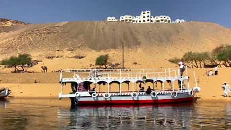Sightseeing-boat-docked-on-Nile-River-along-coast-of-Nubian-Village-in-Egypt