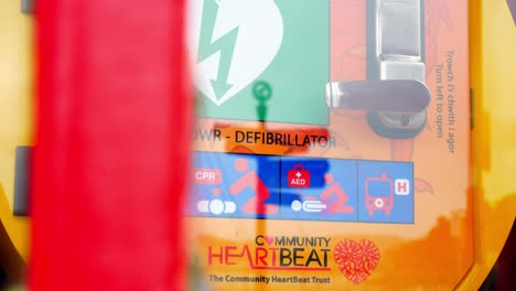 Medical-emergency-cardiology-defibrillator-device-in-old-red-British-public-village-phone-box-slow-right-dolly