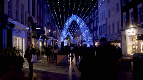 People-enjoying-their-evening-of-shopping-surrounded-by-beautiful-whimsical-LED-Christmas-decorations-in-South-Molton-Street,-Mayfair,-London,-England