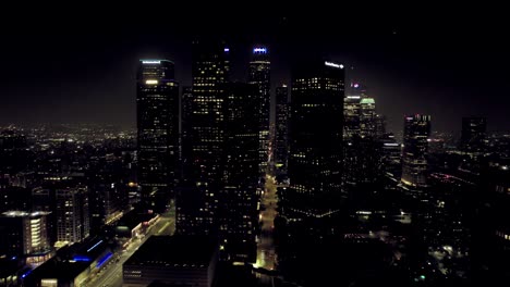 Establishing-Aerial-View-of-Glowing-Lights-of-Downtown-Los-Angeles-City-Skyscraper-Highrise-Office-Towers-at-Nighttime