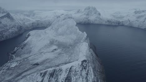 Aerial-view-over-the-snowy-Segla-mountain,-winter-in-Senja,-Norway---reverse,-drone-shot