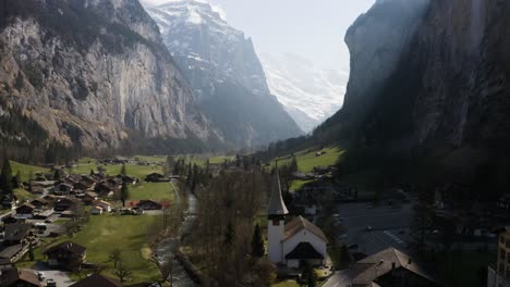 Aerial-turns-to-the-right-and-shows-Lauterbrunnen-town-and-the-waterfall,-Switzerland