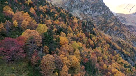 Colorful-forest-in-the-fall-season-at-Lac-d'Espingo-lake-in-Haute-Garonne,-Pyrénées-mountains,-France,-Aerial-flyover-shot