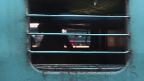 Moving-departing-train-with-passengers-looking-at-camera-out-of-window,-India