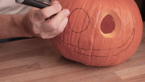 Person-Carves-Eyes-Of-A-Jack-O'-Lantern-On-A-Pumpkin