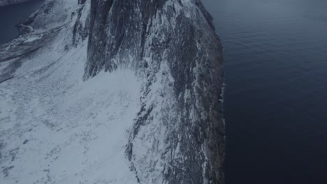 Aerial-view-revealing-the-Segla-mountain,-dark-winter-day-in-Senja,-Norway---tilt,-drone-shot
