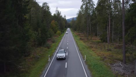 Aerial-view-tracking-a-Volvo-XC40-suv-on-a-mountain-forest-road,-in-Switzerland---reverse,-drone-shot