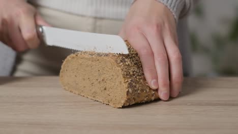 Close-up,-hands-trying-but-failing-to-cut-through-whole-wheat-grain-bread