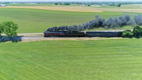 Aerial-View-of-an-Antique-Steam-Engine-and-Passenger-Coaches-Traveling-Along-Countryside-Blowing-Smoke-and-Drone-Traveling-Parallel-To-It,-on-a-Sunny-Summer-Day