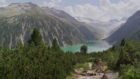 Ein-Kaukasisches-Mädchen-In-Einem-Weißen-Kleid-Geht-Einen-Weg-Hinunter-Zu-Einem-Blauen-See-Und-Einer-Wunderschönen-Berglandschaft