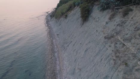 Aerial-tilt-up-shot-showing-the-sea-and-sandy-cliffside-with-medicinal-mud-coast-of-Arillas,-Corfu,-Greece