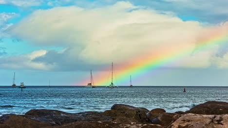 Zeitrafferaufnahme-Des-Pazifischen-Ozeans-Mit-Verankerten-Segelbooten-Und-Regenbogen-Im-Hintergrund---Sonnenreflexion-Nachher-Mit-Wasseroberfläche---Wolken,-Die-Sich-Am-Himmel-Bewegen---Hawaii,-Maui