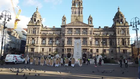 People-walking-past-a-climate-change-protest-in-George-Square,-Glasgow