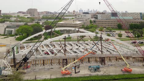 Industrial-cranes-constructing-bridge-in-city-of-Detroit,-aerial-view
