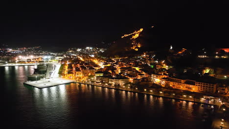Aerial-footage-of-the-Greek-town-of-Nafplio,-Greece-at-night
