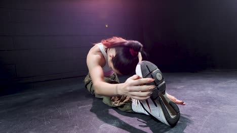 young-female-dancer-with-red-hair-performing-front-splits-showing-his-flexibility-skill-in-studio-with-black-background,-fitness-woman-modern-dance-concept