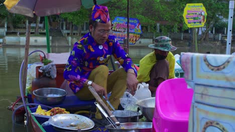 Glücklicher-Mann-Mit-Buntem-Kleid,-Das-Thailändisches-Straßenessen-Von-Einem-Boot-Auf-Dem-Schwimmenden-Markt-Von-Klong-Hae-Verkauft