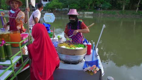 Thailändische-Frau,-Die-Asiatische-Lebensmittel-Auf-Dem-Schwimmenden-Markt-Von-Klong-Hae-Verkauft