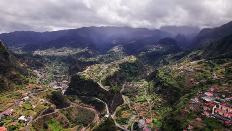 Aerial-panorama-of-village-in-green-volcanic-mountain-valley-landscape,-Madeira