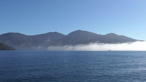 Boot,-Das-Im-Sommer-Durch-Niedrige-Wolken-Am-Frühen-Morgen-über-Einer-Ruhigen-See-Fährt