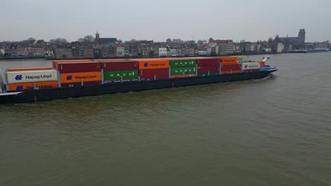29-January-2023---Aerial-Tracking-Shot-Off-Starboard-Side-Of-Scaldis-Container-Ship-Travelling-Along-Oude-Maas-On-Overcast-Day-In-Dordrecht