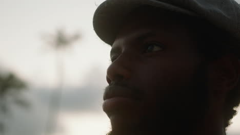 Close-up-of-a-young-black-man-on-an-exotic-beach-with-palm-trees-in-the-background