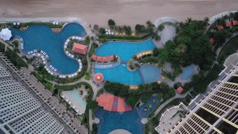 Grand-Hotel-Ho-Tram,-Vietnam-top-down-Aerial-view-featuring-buildings,-swimming-pools-and-beach-in-beautiful-light