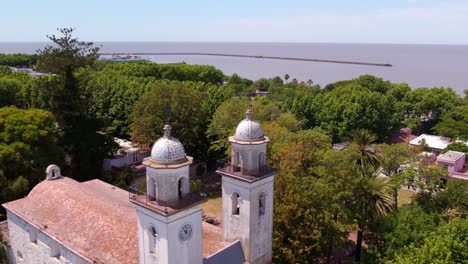 Aerial-view-dolly-in-of-the-Basilica-of-the-Blessed-Sacrament-in-Colonia-del-Sacramento-in-Uruguay-on-a-sunny-day,-structural-domes-of-the-church